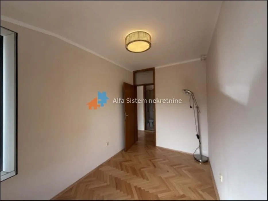 Empty room with hardwood flooring and ceiling light fixture.