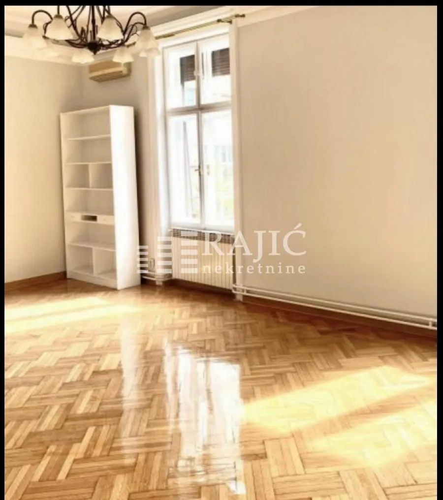 Empty room with parquet flooring and a white bookshelf.
