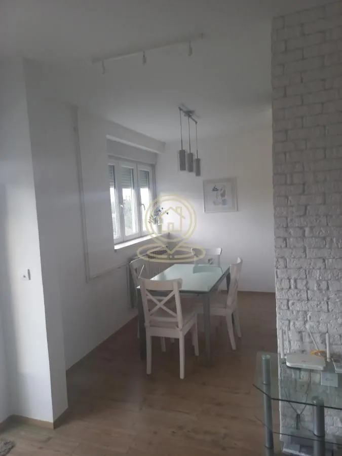 Dining area with a table and white chairs by the window.