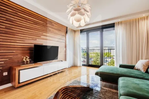 Living room with wooden wall paneling, television, and a green sectional sofa. - image 3