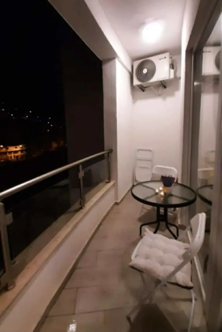 Furnished balcony with a table, chairs, and an air conditioning unit.