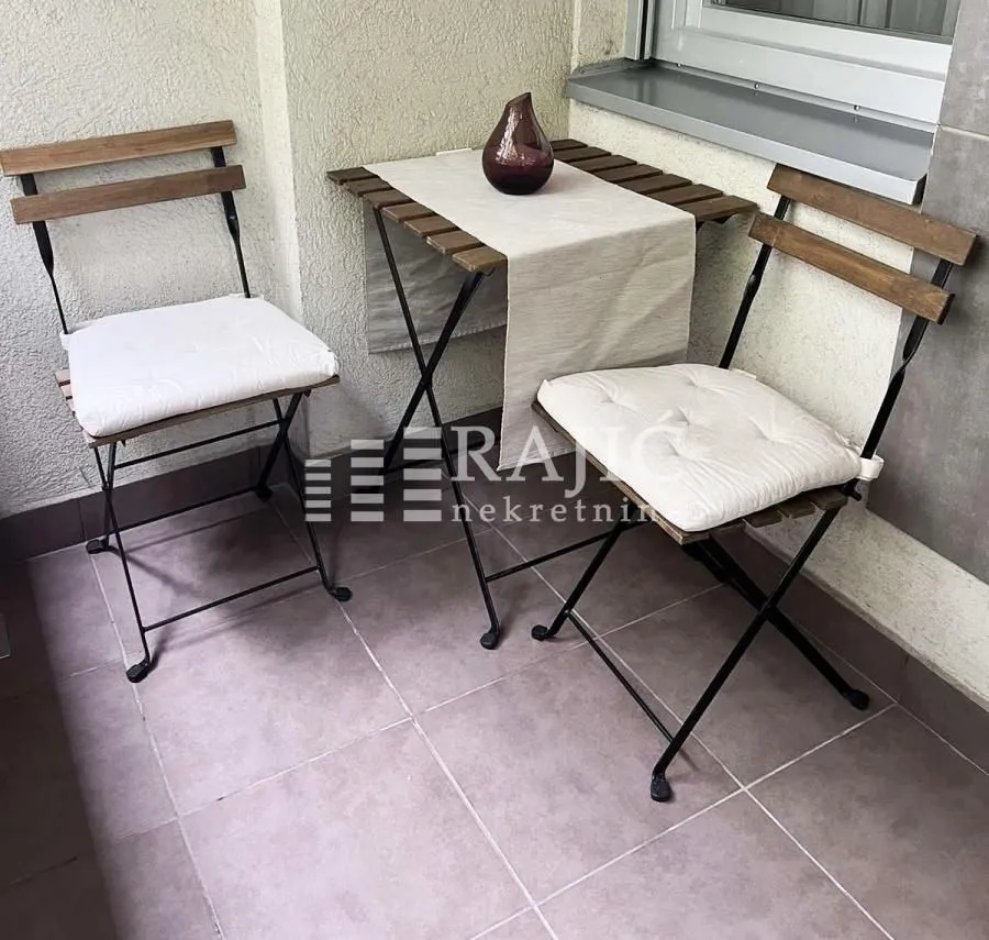 Small furnished balcony with a table and two chairs.