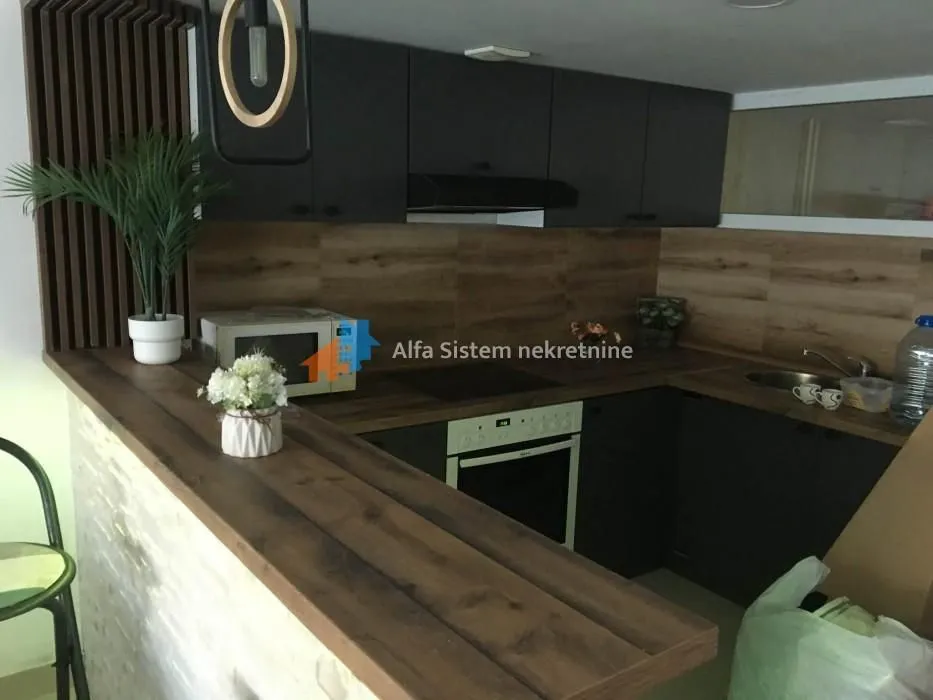 Modern kitchen with dark cabinets, wooden countertops, and a breakfast bar.