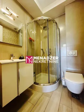 Small bathroom with a shower cabin, washbasin, and toilet. - image 6