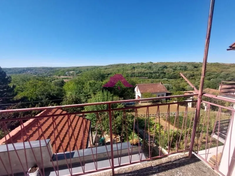 Pogled sa balkona na okolno zelenilo i susedne objekte.