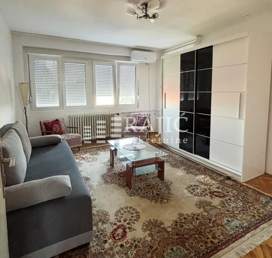 Living room with a sofa, large wardrobe and windows.