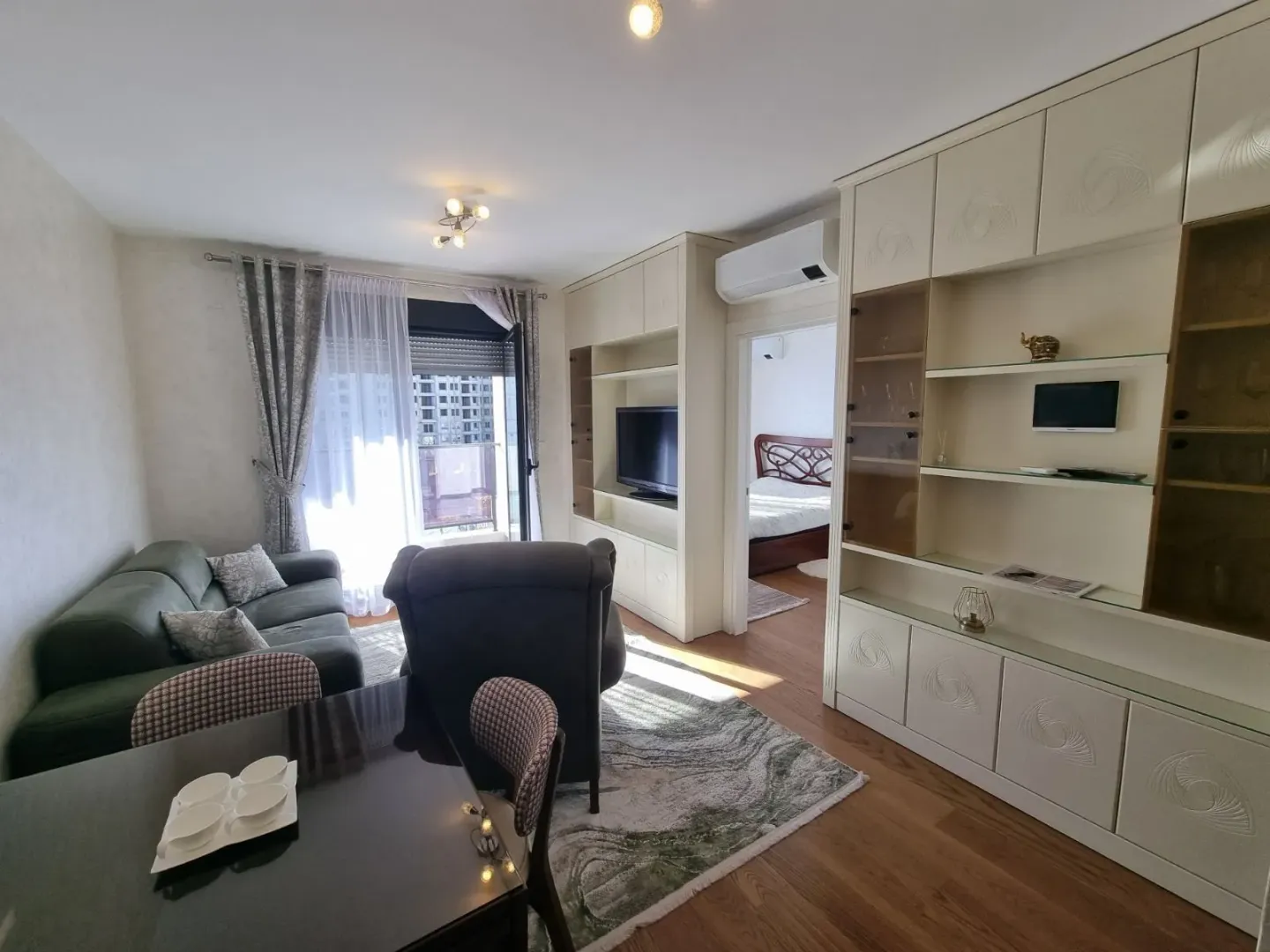 Bright living room with furniture and a view into the bedroom.