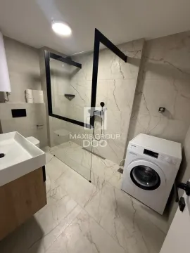 Modern bathroom with a walk-in shower, washbasin, and washing machine. - image 17