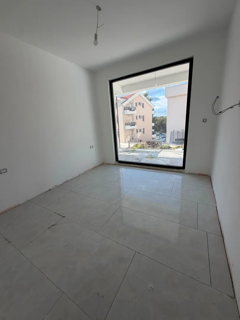 Empty room with ceramic floor tiles and a large window.