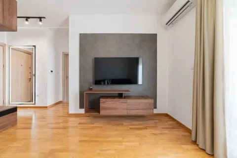 Moderan dnevni boravak sa drvenim podom, televizorom na zidu i komodom. - image 7