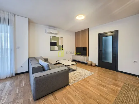 Dnevna soba sa sivom garniturom, stočićem i televizorom na zidu. - image 13