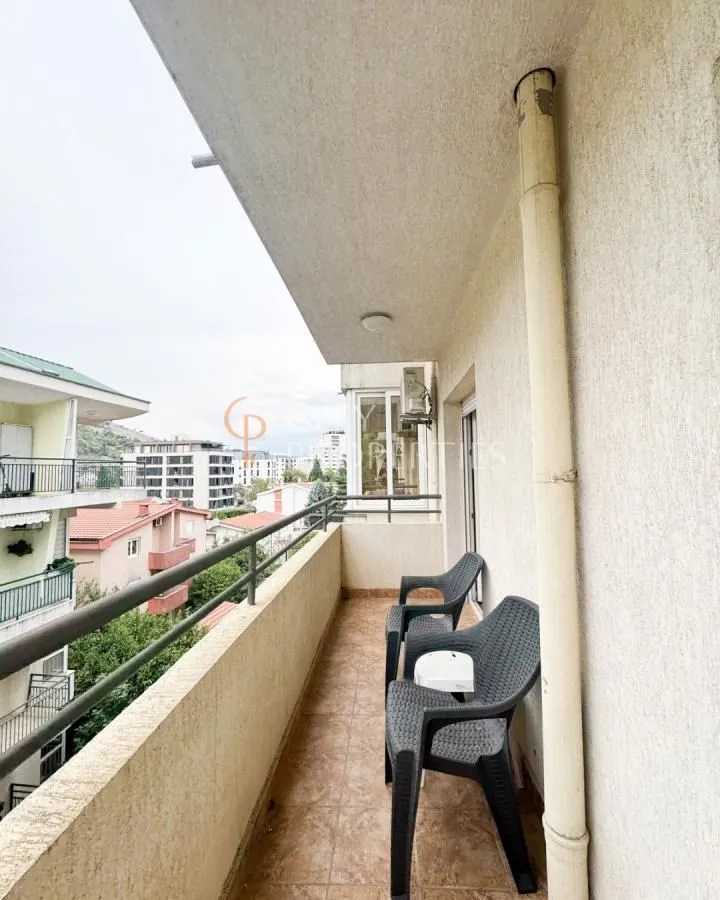 Covered balcony with seating furniture and a view of the surrounding buildings.