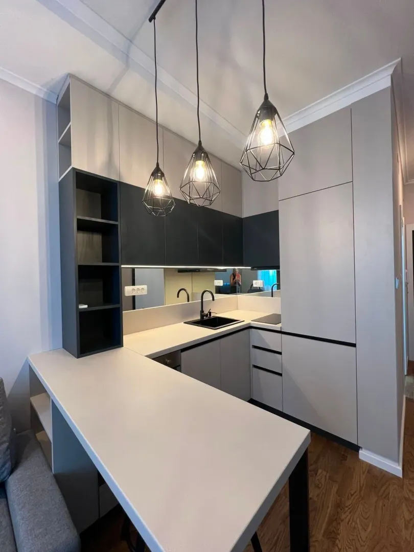 Modern kitchen with grey cabinets and pendant lights.