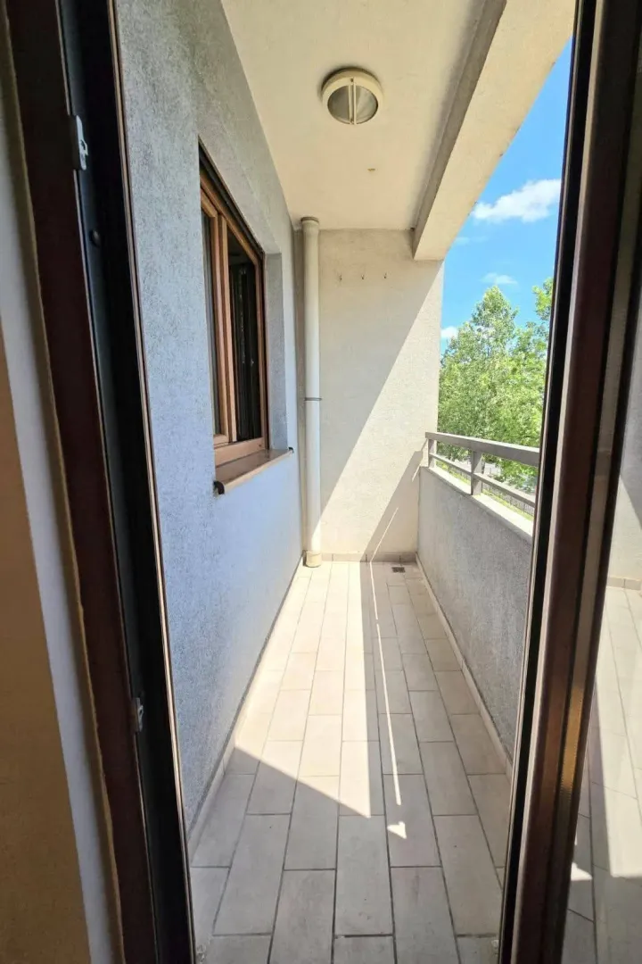 Pogled na natkriveni balkon sa popločanim podom i ogradom.