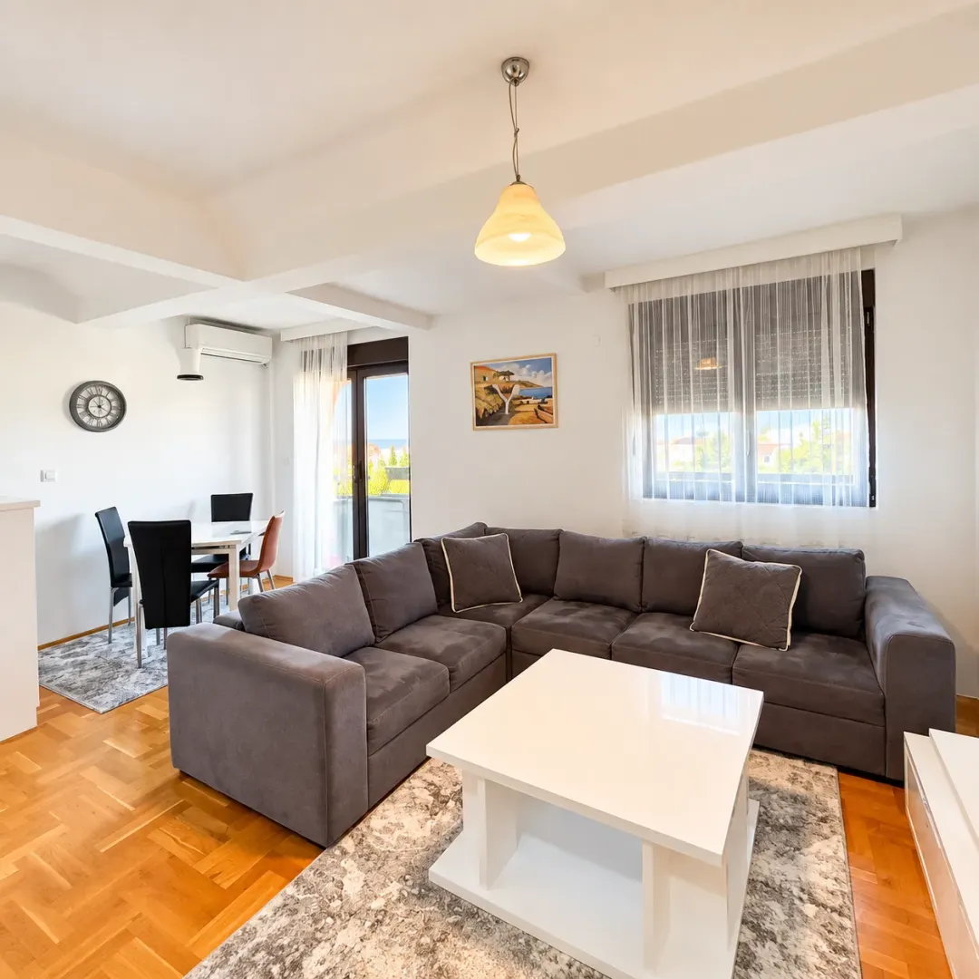 Bright living room with a sectional sofa and a dining area in the background.
