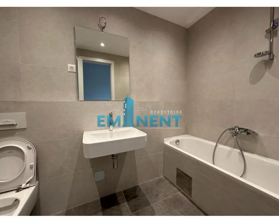 Modernly equipped bathroom with a bathtub, washbasin, and toilet.