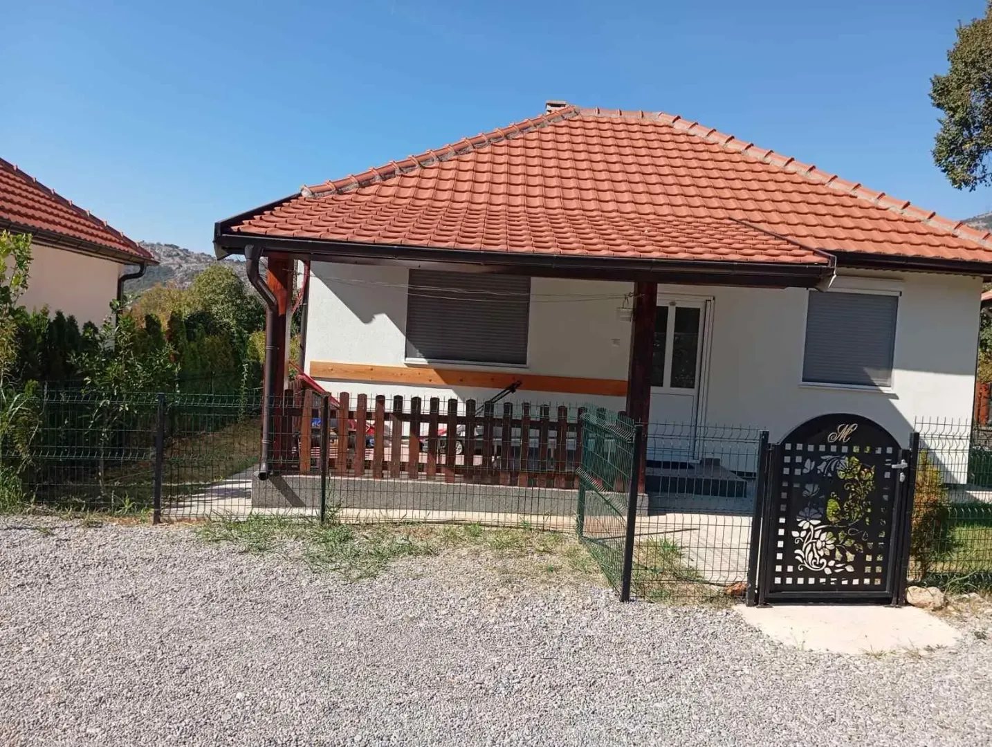 Exterior view of a single-story house with a yard and fence.