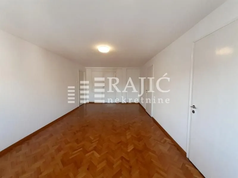 Empty room with parquet flooring and white walls.
