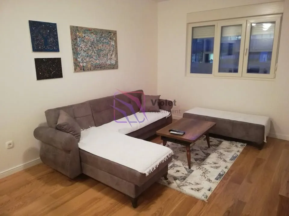 Living room with a sectional sofa, coffee table, and paintings on the wall.