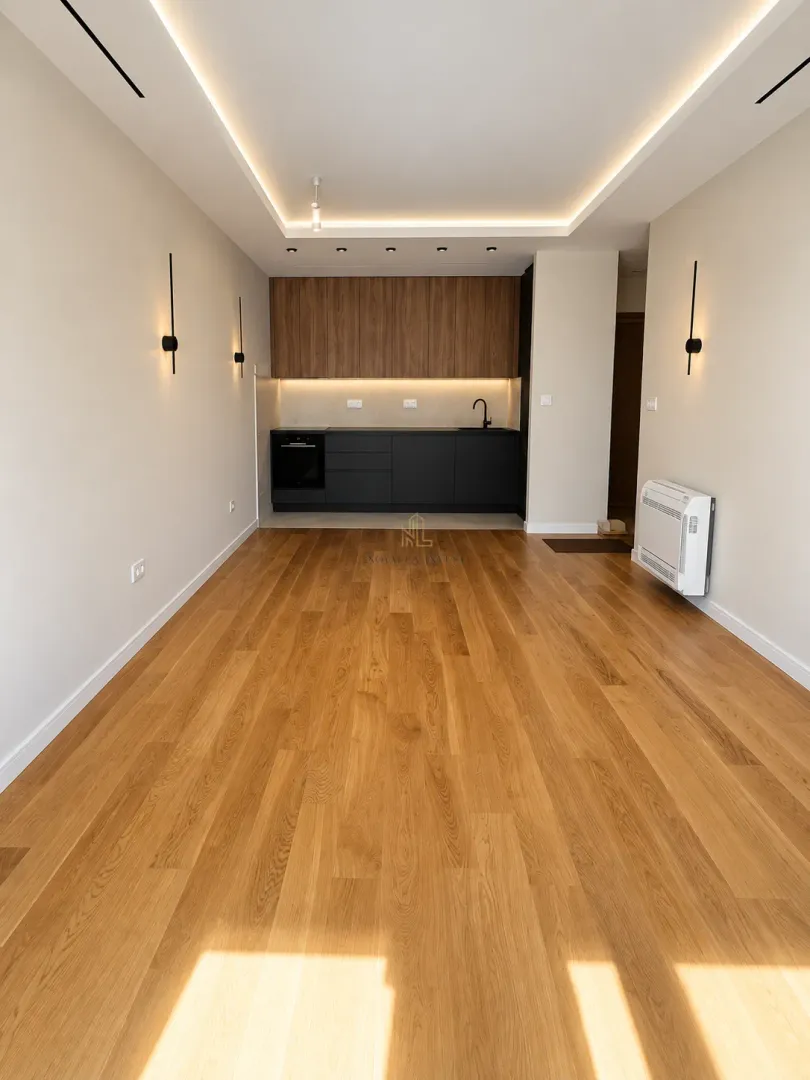 Spacious living room with wooden flooring and a view of the fitted kitchen in the background.