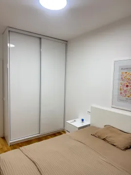Spavaća soba sa bračnim krevetom, bijelim garderoberom sa kliznim vratima i noćnim stočićem. - image 6