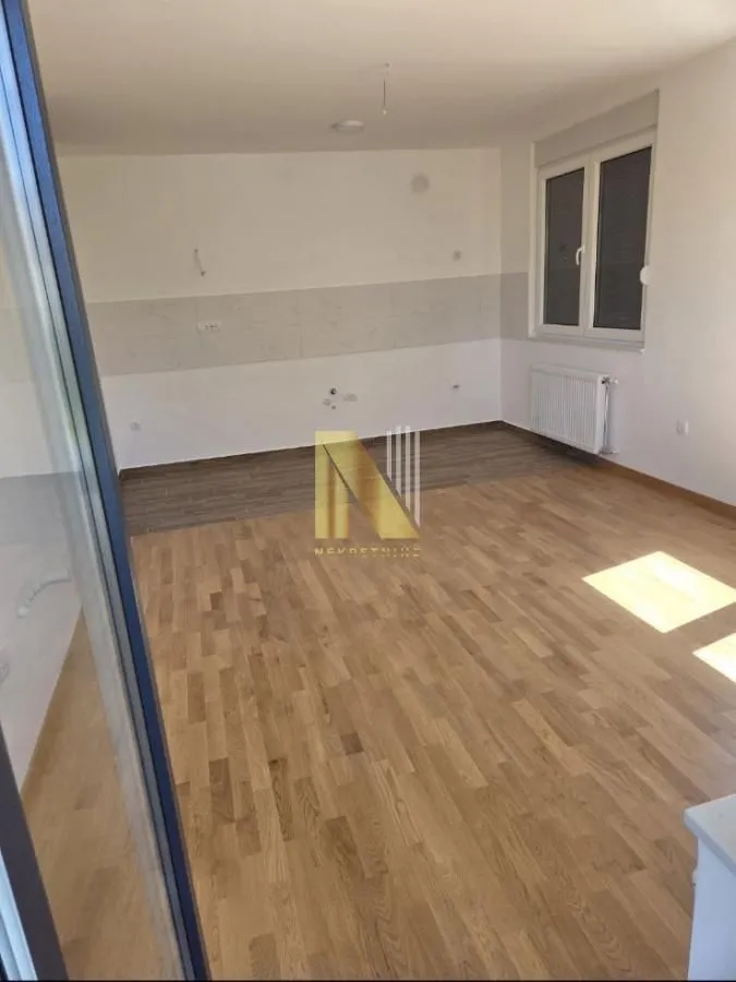 Prazna kuhinja sa pločicama na zidu i parketom na podu.
