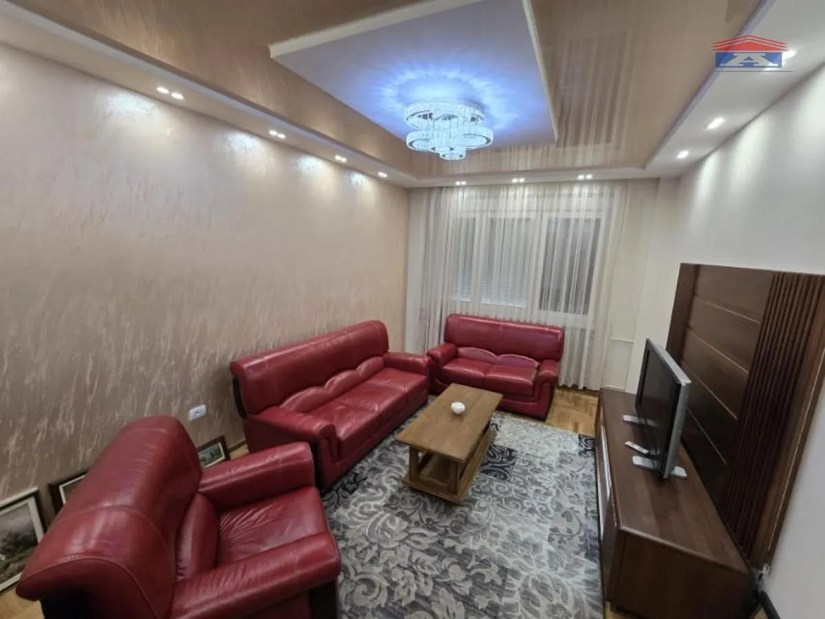 Living room with red leather sofas, a wooden coffee table, and a TV.