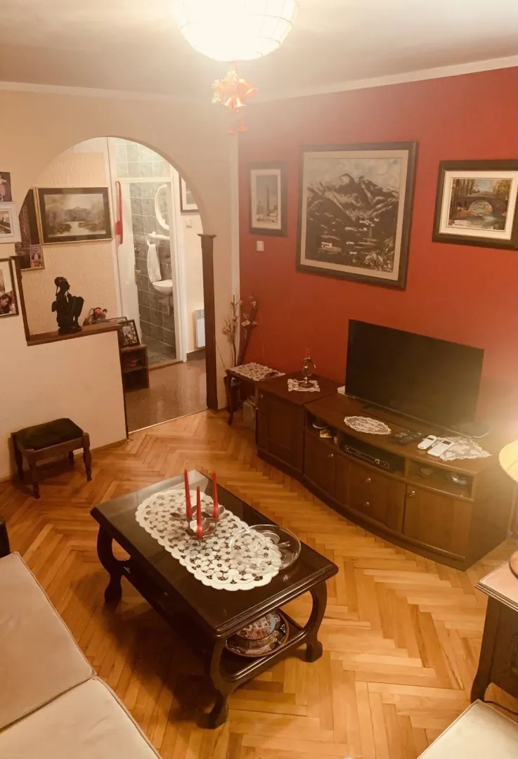 Living room with wooden furniture, a television, and parquet flooring.