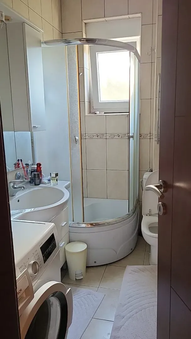 Manje kupatilo sa tuš kabinom, umivaonikom i veš mašinom.