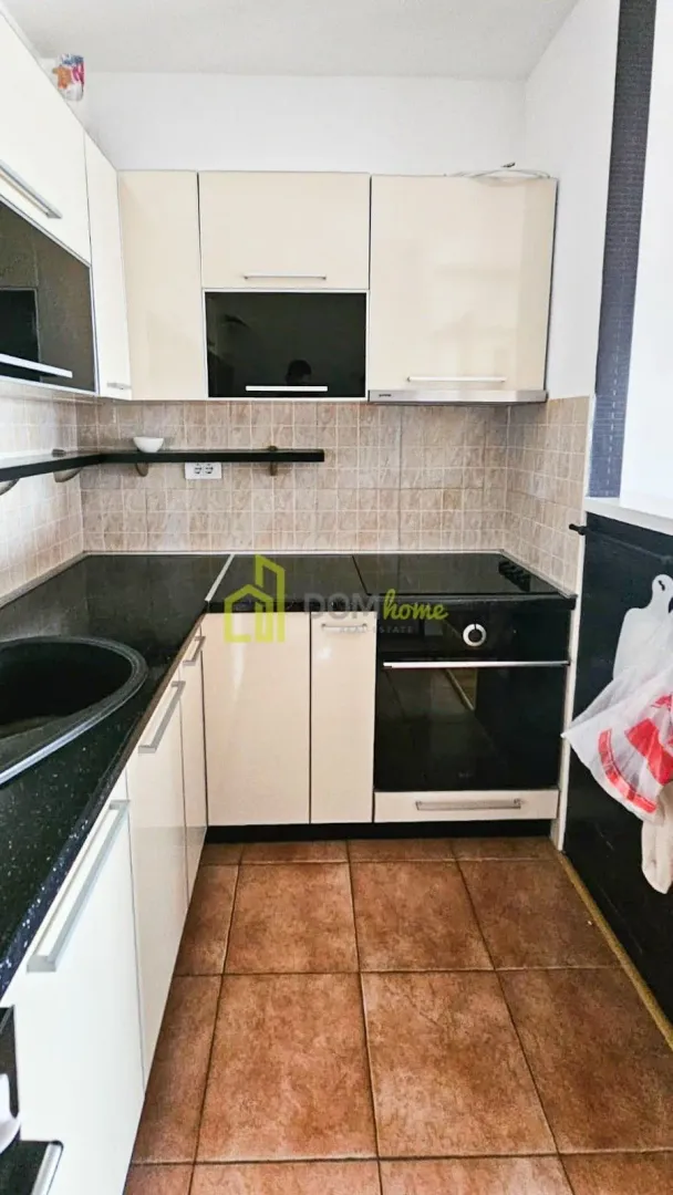 Small kitchen with white cabinets, dark countertop, and built-in appliances.