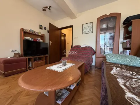 Nameštena dnevna soba sa garniturom, televizorom i drvenim nameštajem. - image 6