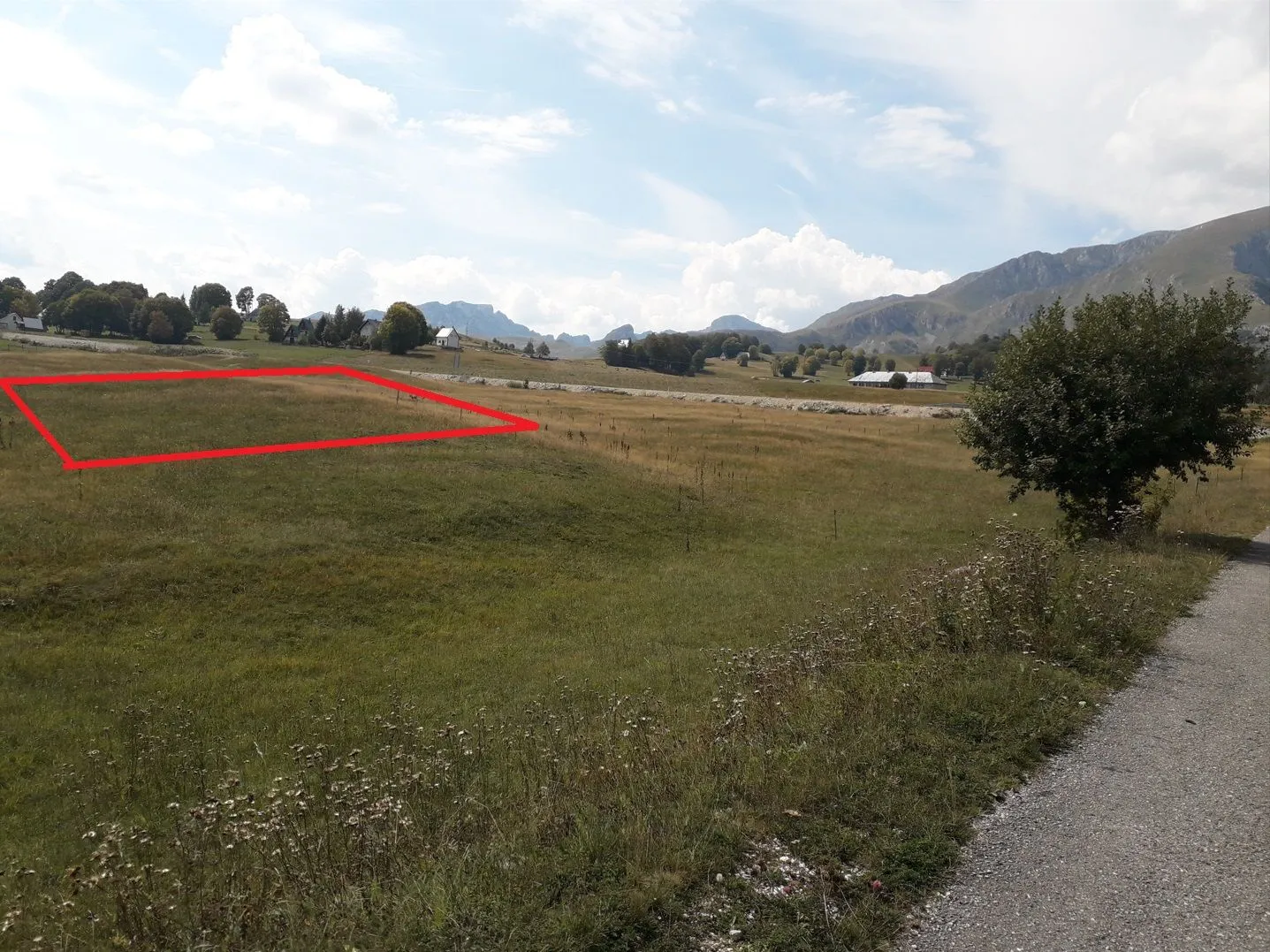 Pogled na plac sa označenom granicom i planinskim pejzažem u pozadini.