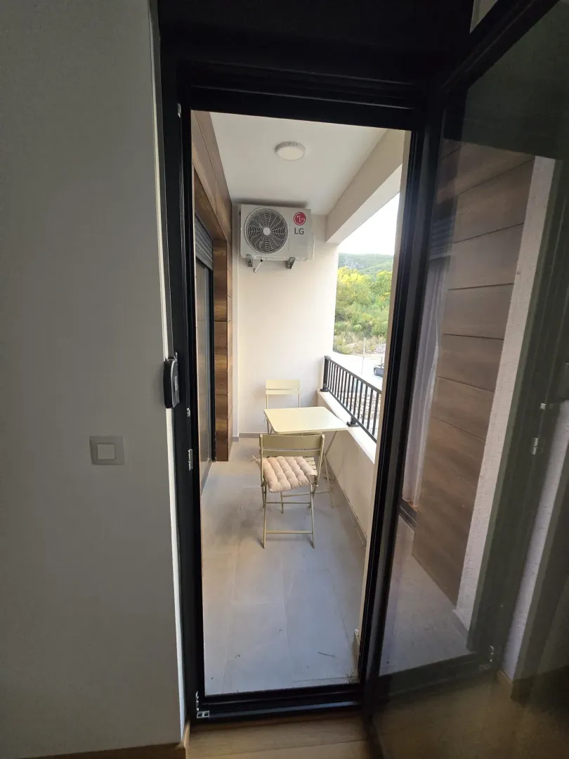 View from the room onto a furnished balcony with a table and chairs.
