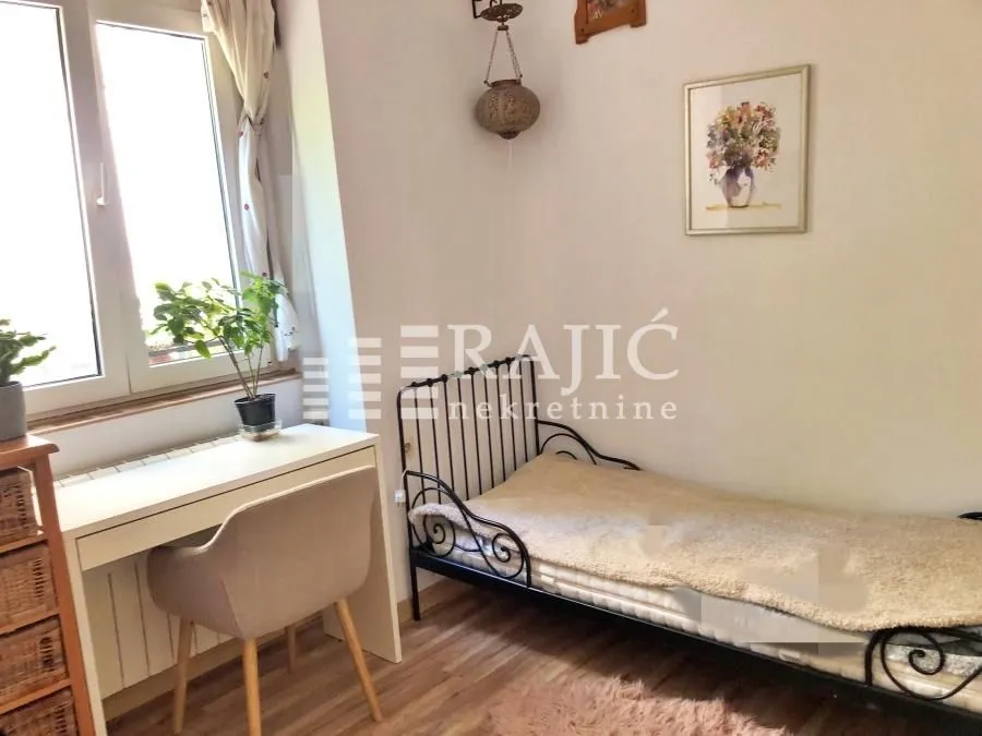 Smaller bedroom with a bed, desk, and a window.