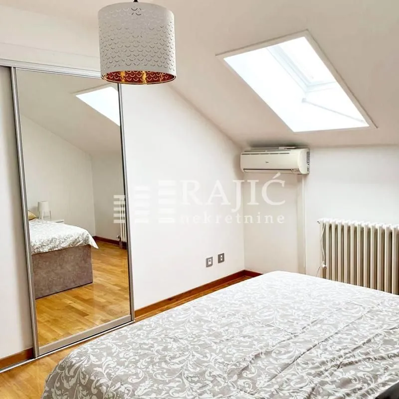 Attic bedroom with a bed, mirrored wardrobe, and a skylight.