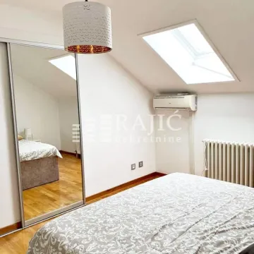 Attic bedroom with a bed, mirrored wardrobe, and a skylight. - image 9