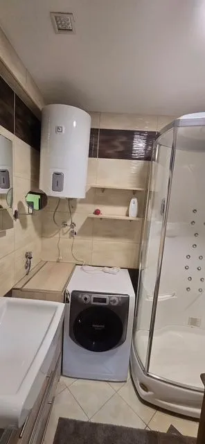 Manje kupatilo sa tuš kabinom, umivaonikom i veš mašinom.