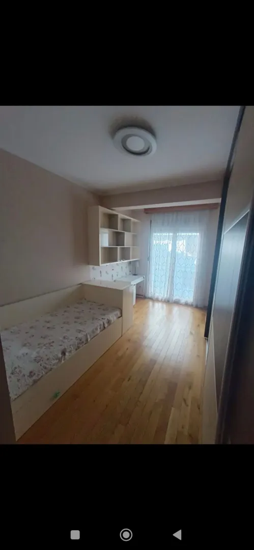 Children's bedroom with a bed, desk, and wooden flooring.