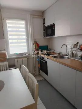 Manja kuhinja sa belim elementima i trpezarijskim stolom pored prozora. - image 5