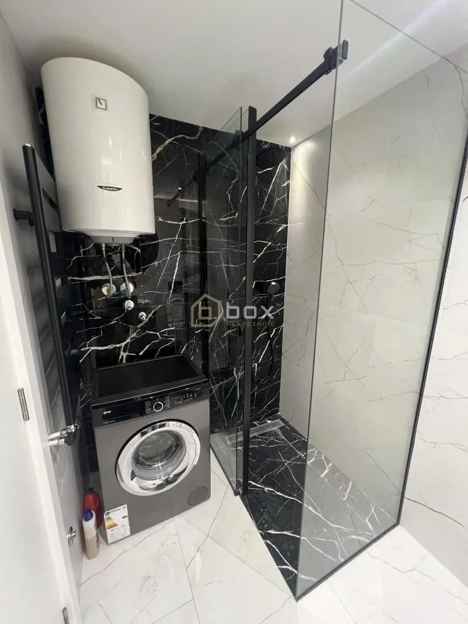 Modern bathroom equipped with a walk-in shower and a washing machine.