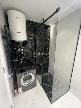 Modern bathroom equipped with a walk-in shower and a washing machine. - image 11