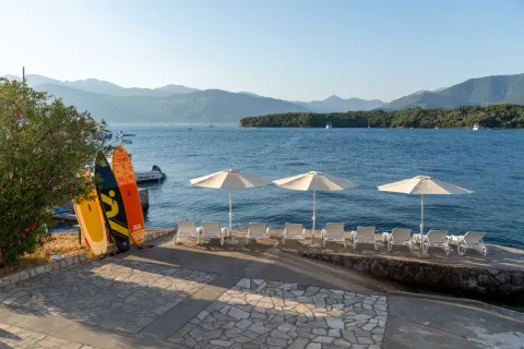 Pogled na popločanu terasu sa ležaljkama i suncobranima pored mora. - image 2