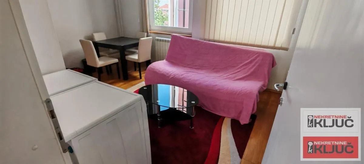 Dnevni boravak sa garniturom, stočićem i trpezarijskim stolom u pozadini.