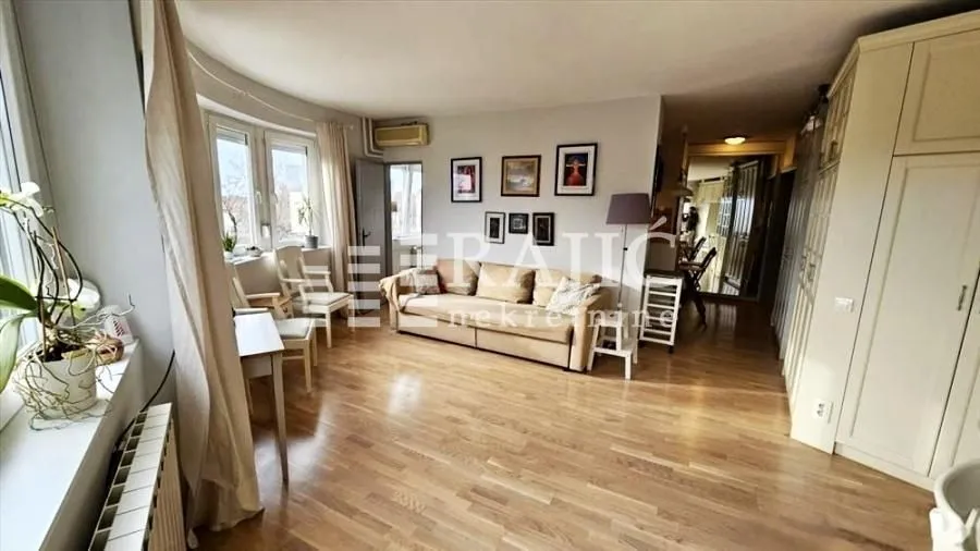 Spacious living room with a sofa and wooden flooring.