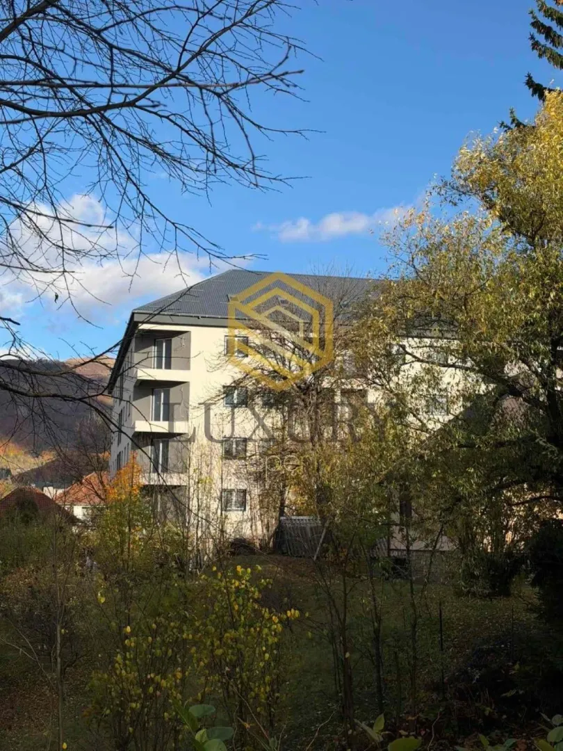 Eksterijer stambene zgrade okružene zelenilom.
