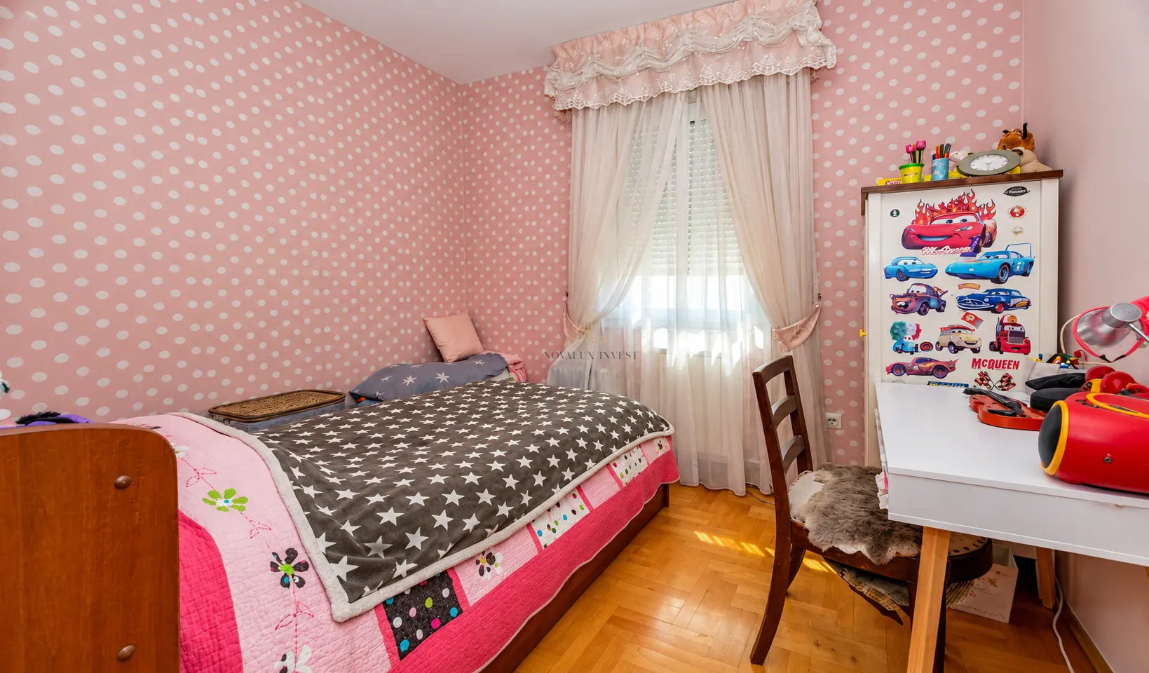 Children's bedroom with a bed, desk, and polka dot wallpaper.