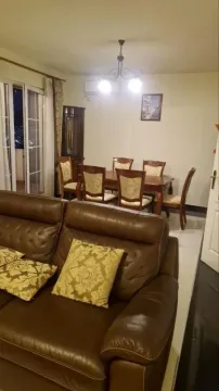 Living room with a sofa set and a dining area in the background. - image 6