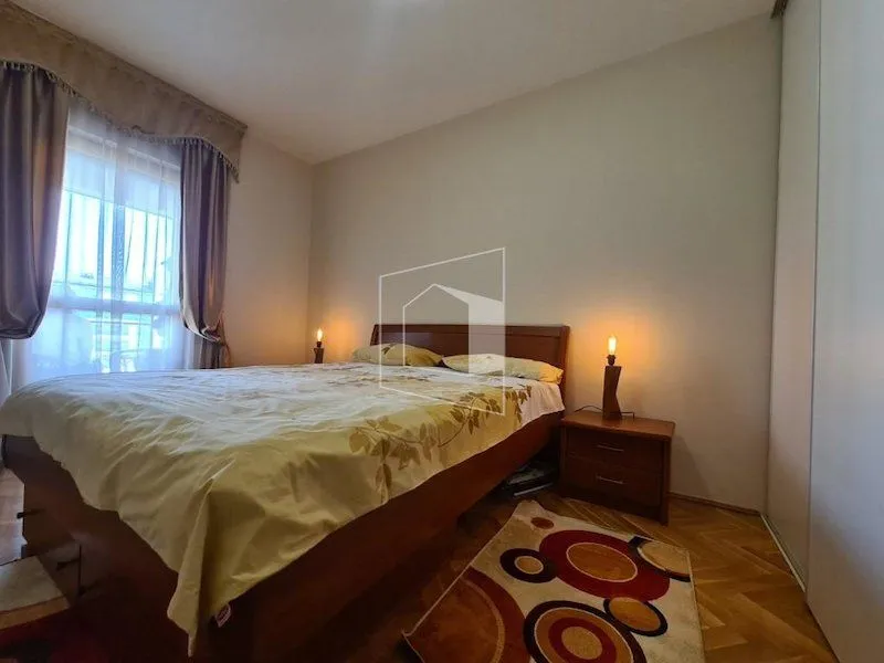 Furnished bedroom with a double bed, wardrobe, and a window with curtains.