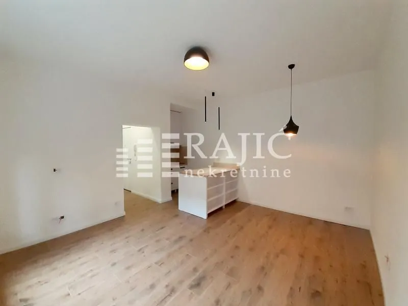 Empty room with a kitchen unit and wooden flooring.