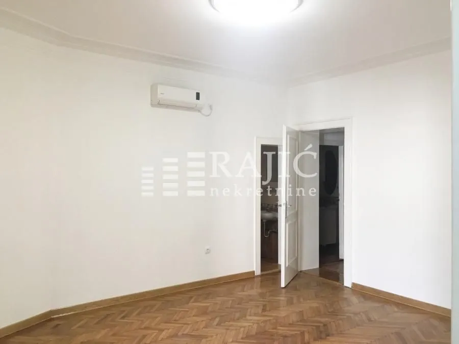 Bright room with parquet flooring and an air conditioning unit on the wall.